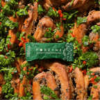 FODZYME single-serve packet reading 'sprinkle to make food painless' resting on a dish of garlic bread with herbs and chili.