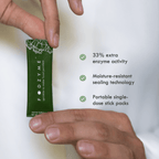 Hands holding a FODZYME single-serve stick pack. Text highlights three features: 33% extra enzyme activity, moisture-resistant sealing technology, and portable single-dose stick packs.
